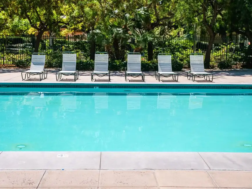 Relax by a tranquil outdoor pool surrounded by sun loungers and lush greenery.